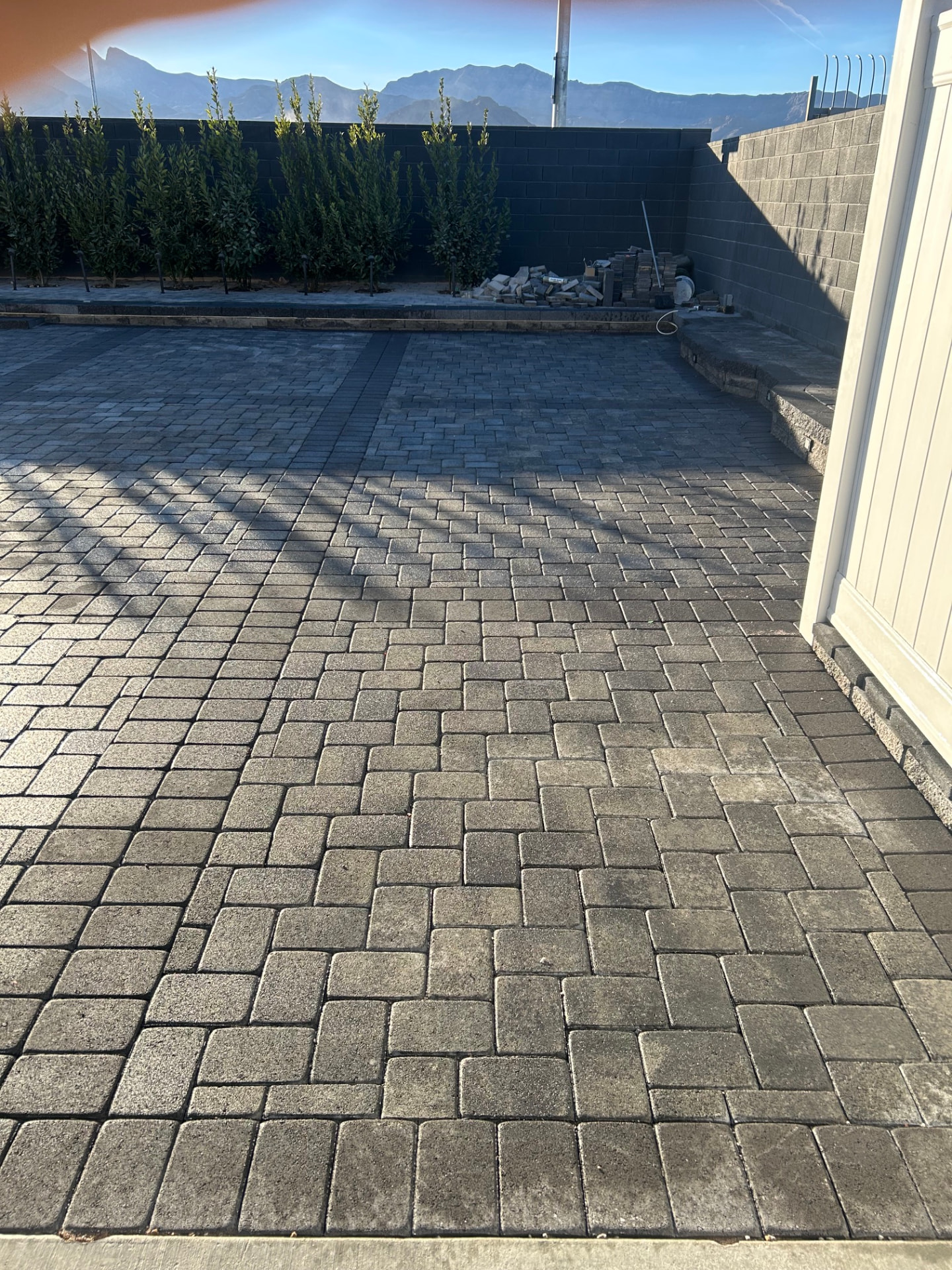 Large paver patio with new privacy hedge and mountain views